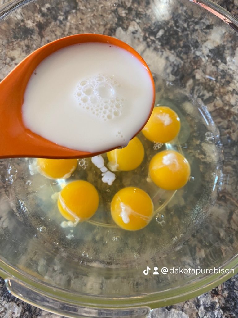 adding milk to a bowl of eggs