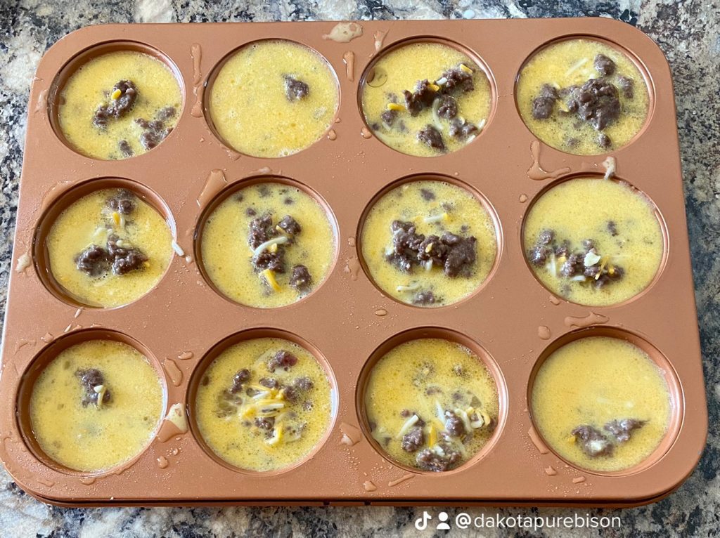 a muffin tin filled with an uncooked egg, sausage and cheese mixture before baking