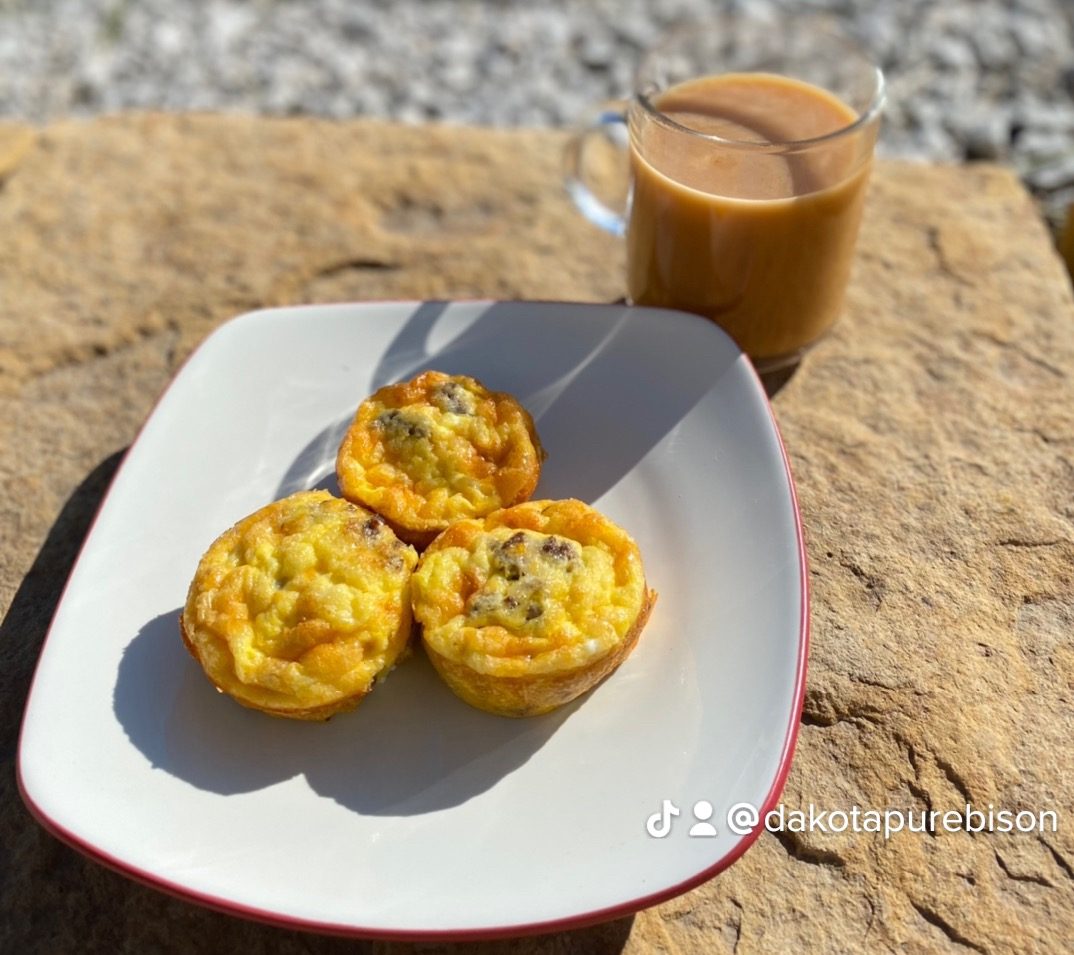 three egg muffins on a plate next to a glass of coffee